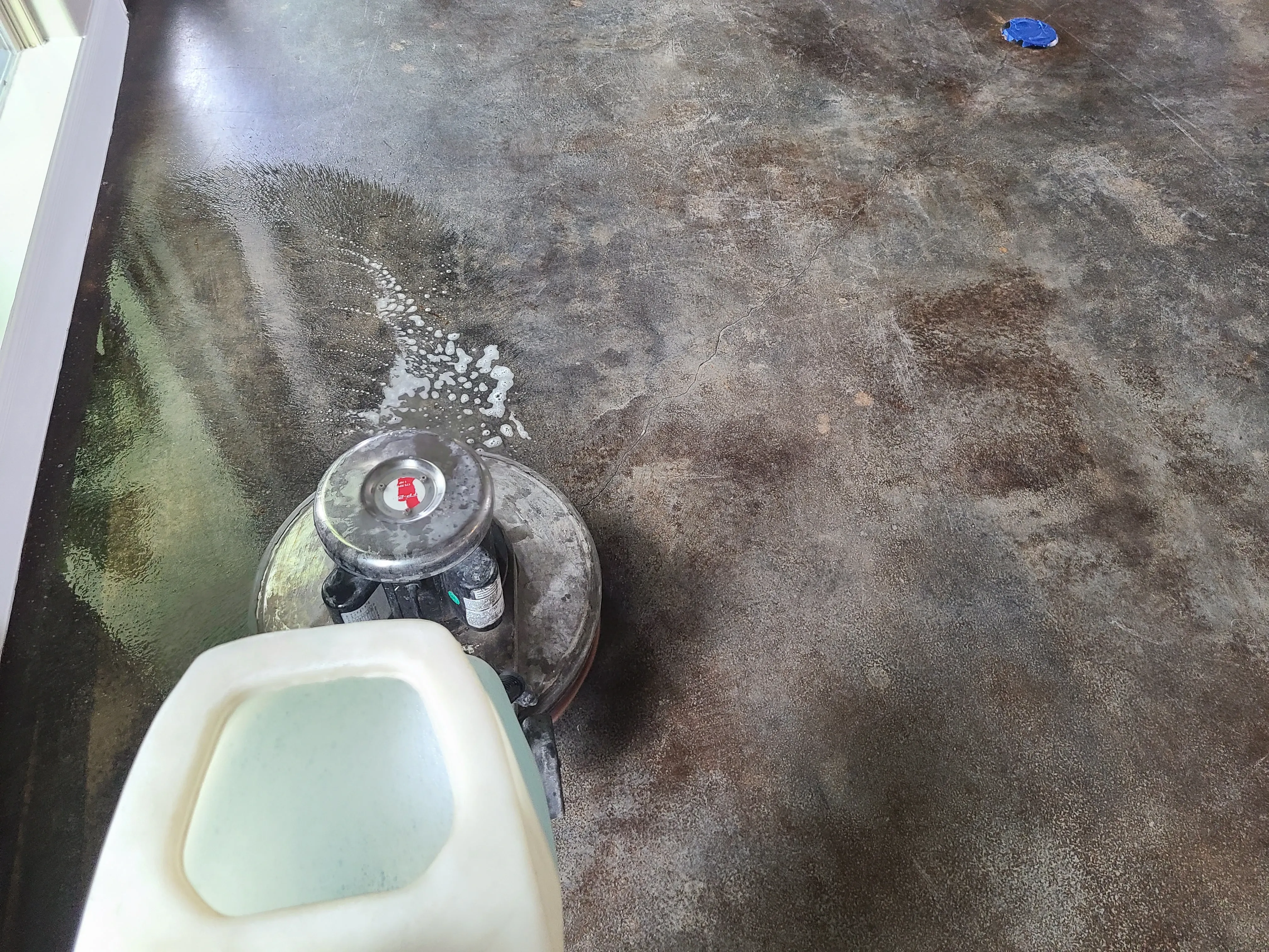 Concrete floor mid-clean during a top coat waxing service