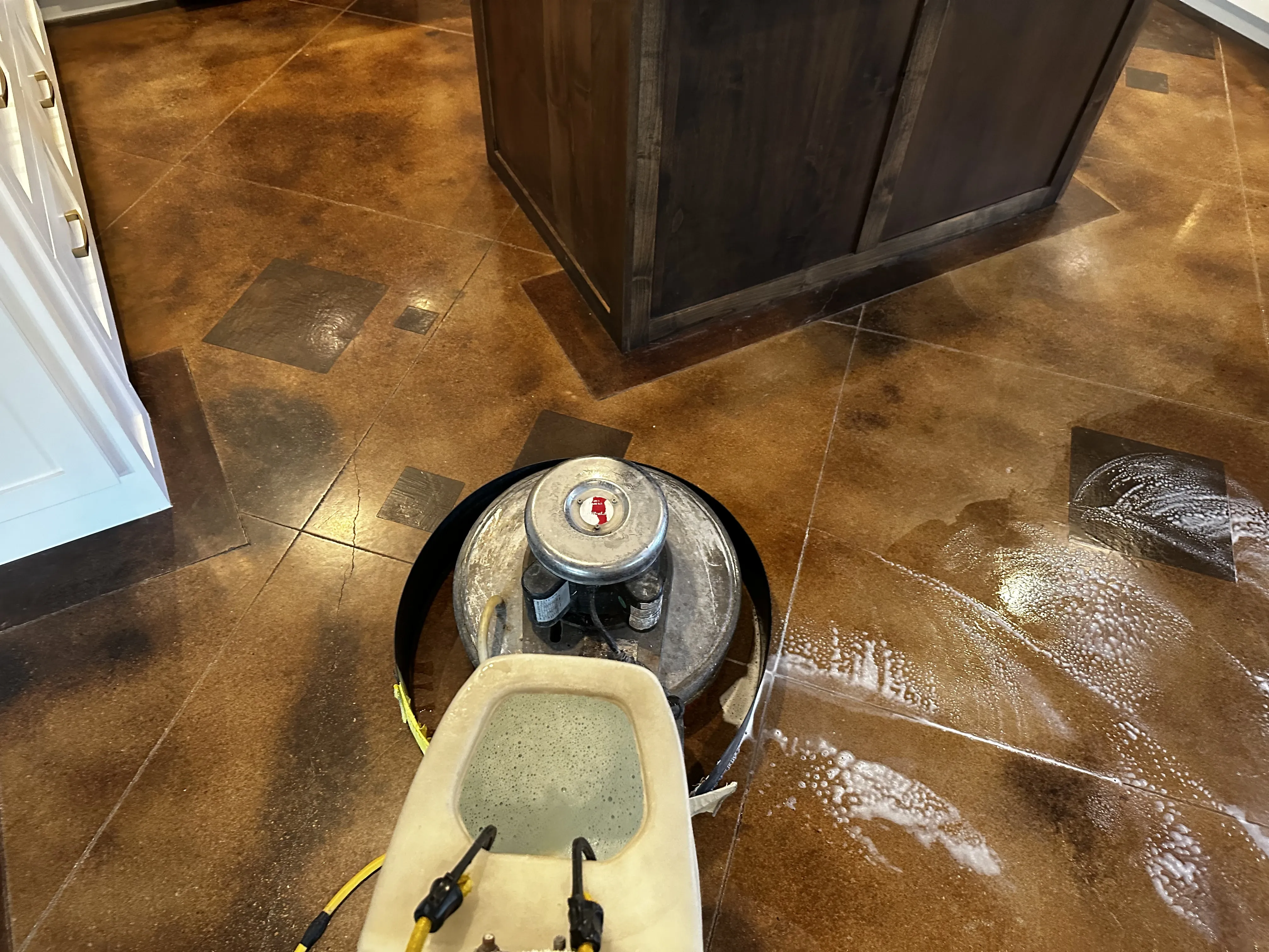 Residential concrete floor mid-cleaning, with suds formed on the surface